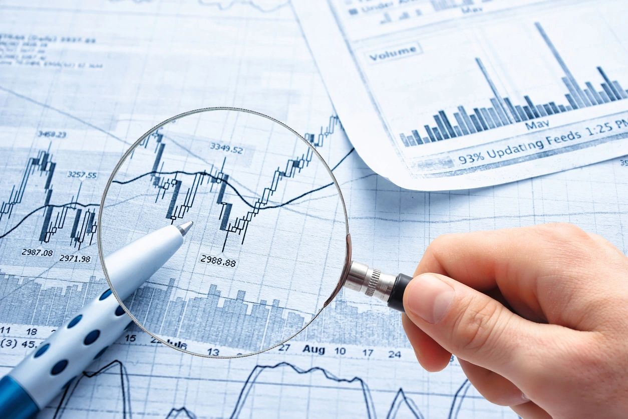 Magnifying glass analyzing financial charts